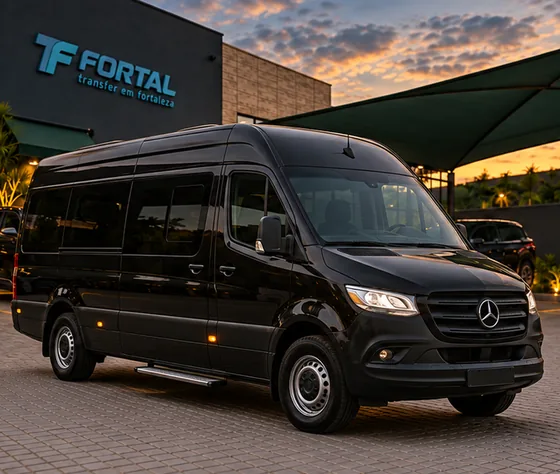 Van Mercedes-Benz Sprinter preta estacionada diante de uma fachada com o logo Fortal, ao entardecer